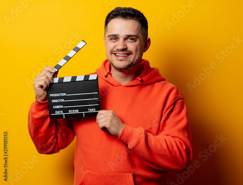 Happy man with clapper on yellow background