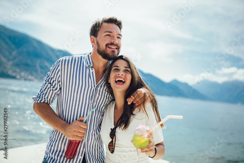 Young couple eating fruit on the beach- summer party with friends and healthy food concept