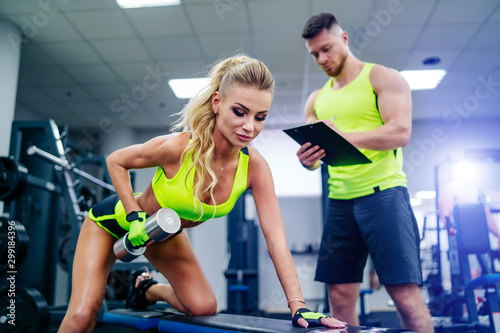 Obraz na plátně Trainer and client doing workout at gym with dambbell