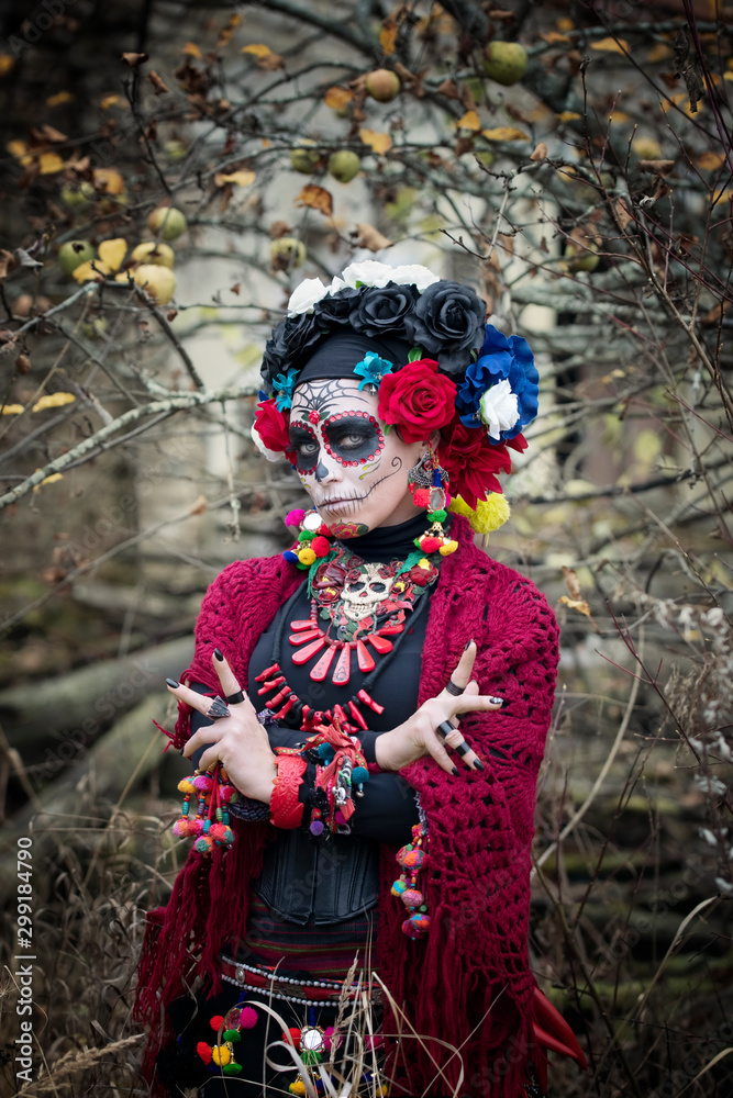 Girl in carnival mask for a traditional Mexican holiday of the day of the dead under an old apple tree Girl in carnival mask for a traditional Mexican holiday of the day of the dead under an old apple tree