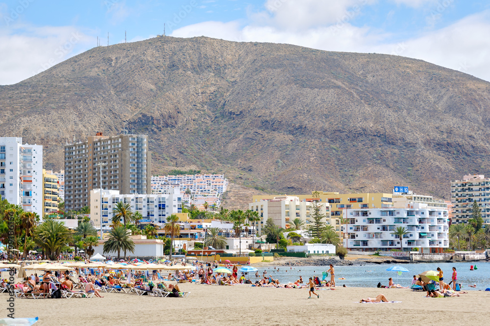 People sunbathing on sandy beach of Playa de los Cristianos, Tenerife, Canary Islands, Spain