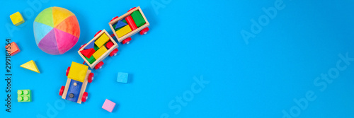 Baby kids toys banner background. Wooden train, soft ball and colorful blocks on blue background