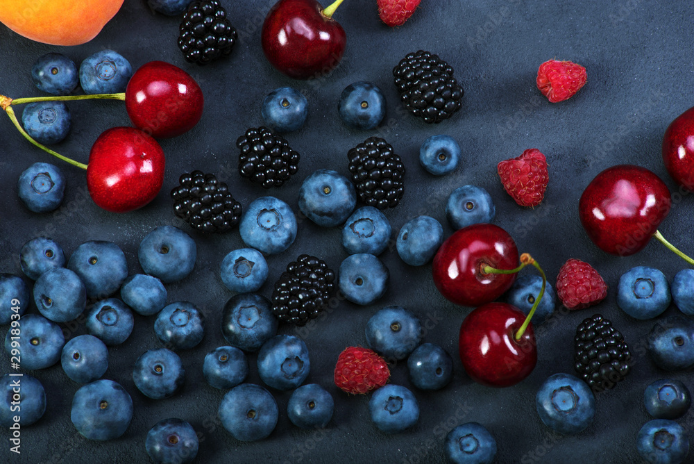 Blackberries,blueberries,raspberries,cherries on black concrete background. Healthy food