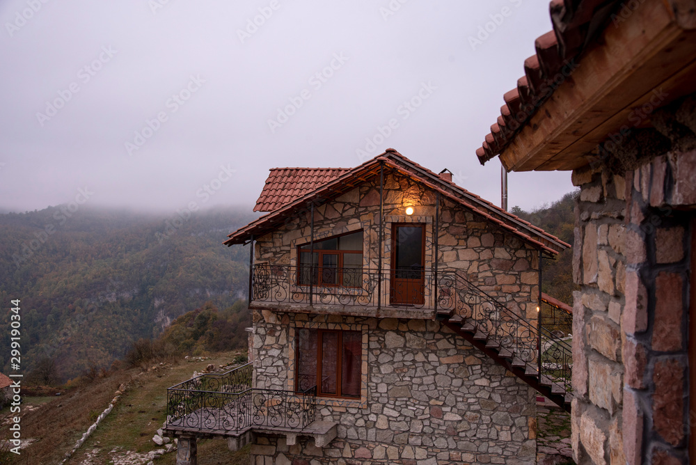 The corner of the house with balcony and a tiled roof on a background of foggy mountain landscape.