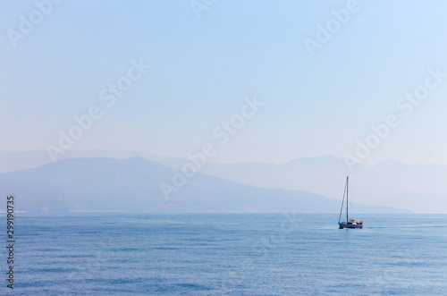 yacht on the background of the coast and mountains from the sea in the morning fog