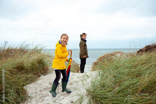 Foto Two happy teenager siblings staing with ambrella on coast of Baltic sea at windy
