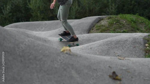 SLOW MOTION Dynamic close-up shot of woman in torn green jeans riding a skateboard
