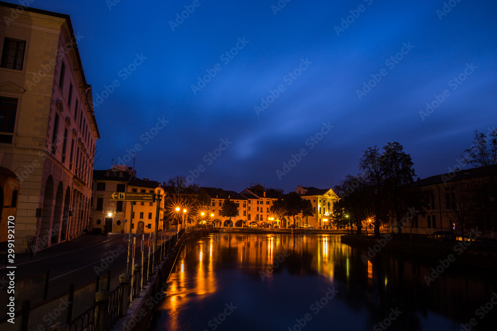 Picturesque view on the Sile river from the university bridge Ponte dell'Universita with lights reflections on the water at night Treviso Italy