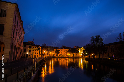 Picturesque view on the Sile river from the university bridge Ponte dell'Universita with lights reflections on the water at night Treviso Italy