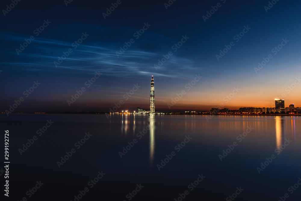 Noctilucent clouds. Shining clouds. Night Silver clouds at summer night in Saint-Petersburg. Beautiful luminous clouds in the dusk in big city. Night cityscape with skyscraper.