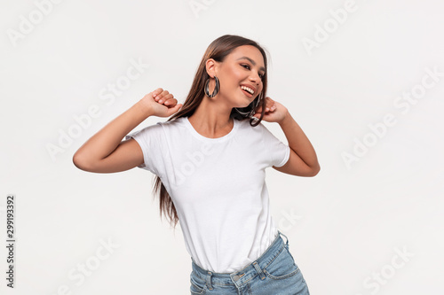 Beautiful african-american teenager in a white t-shirt and blue jeans dancing isolated over white background.