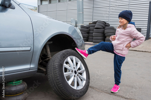 Little girl at a car service. Replacing wheels on a car. Repair service.