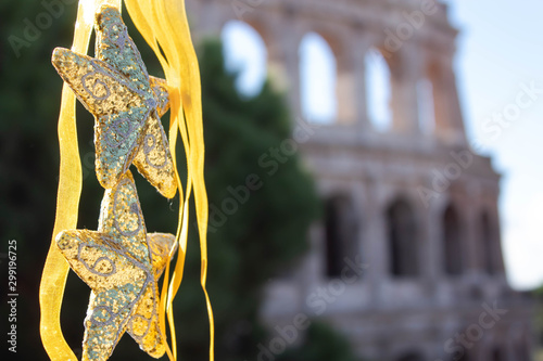 Christmas decorations in the form of gold stars on the background of the Colosseum, Rome. Christmas and New Year in Italy