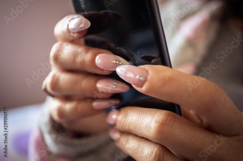 Women's hands with manicured nails holds smartphone