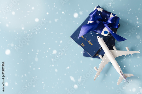 Christmas or New Year travel concept. Toy airplane with passports and gift box on blue background.