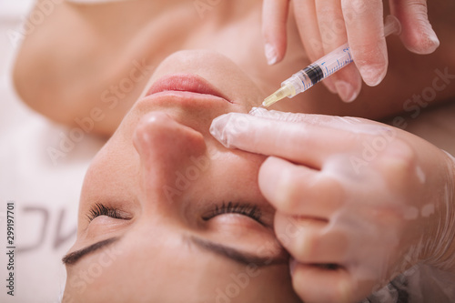 Cropped shot of a beautiful young woman getting face filler injections at beauty clinic. Cosmetologist injecting hyaluronic acid into skin of a client during rejuvenating treatment session