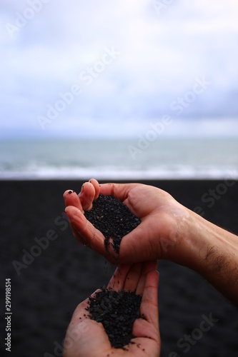 Manos dejando caer arena negra de la playa de Islandia