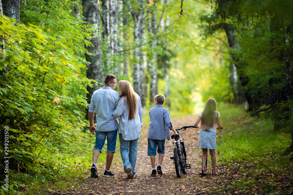 Rear view - a family with two children walks in park