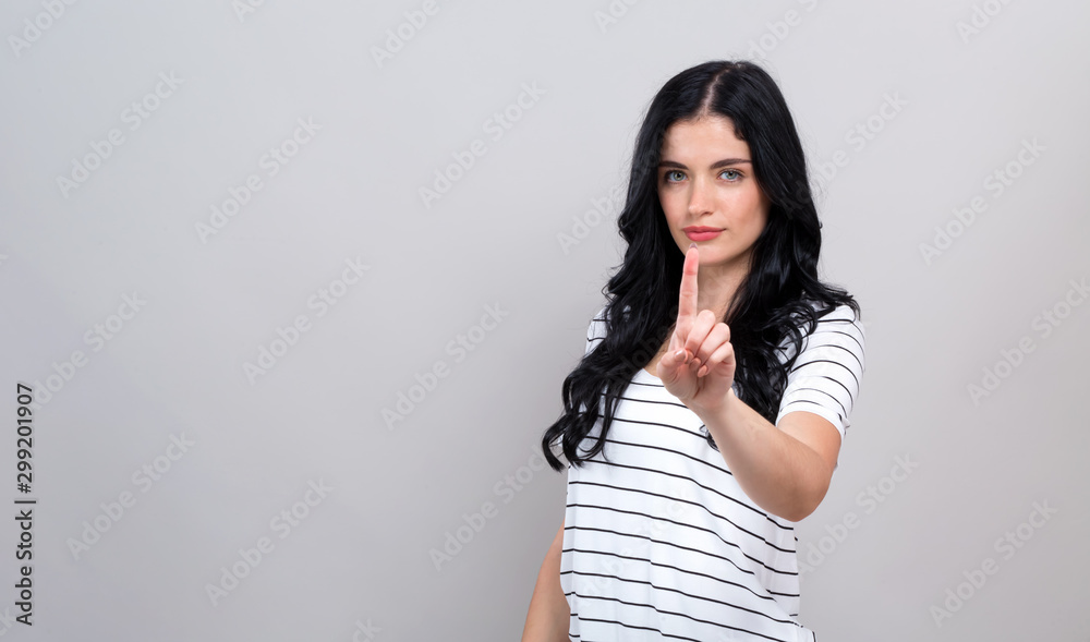 Young woman pointing at something on a gray background Young woman pointing at something on a gray background