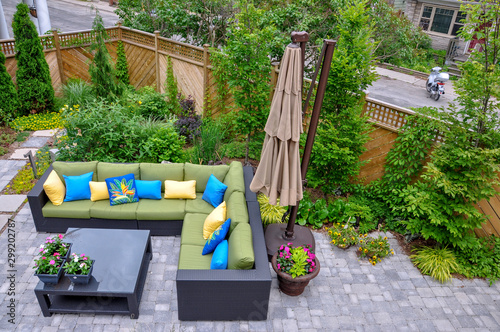 A beautiful small, urban backyard garden featuring a tumbled paver patio, flagstone stepping stones, and a variety of trees, shrubs and perennials add colour and year round interest. 