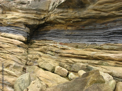 Sandstone and shale layers and textures in a coatal cliff worn by wave action.