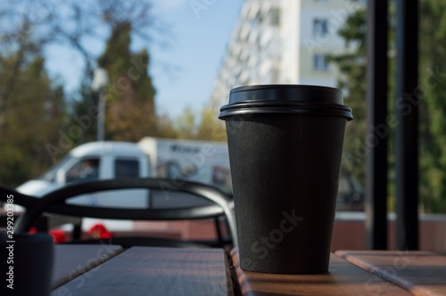 Hot coffee in a paper Cup on a table in a street cafe