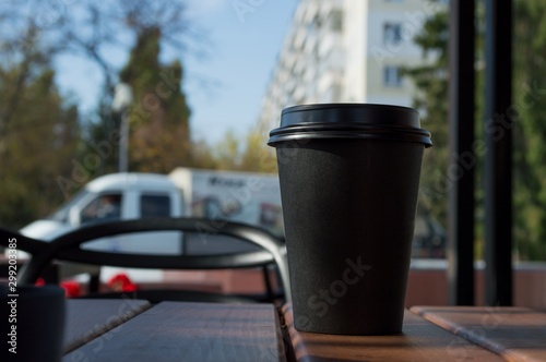 Hot coffee in a paper Cup on a table in a street cafe photo