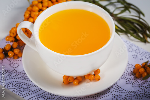 sea-buckthorn tea in white cup with berries with branch on natural napkin. a source of nutritional vitamins in the fall and winter