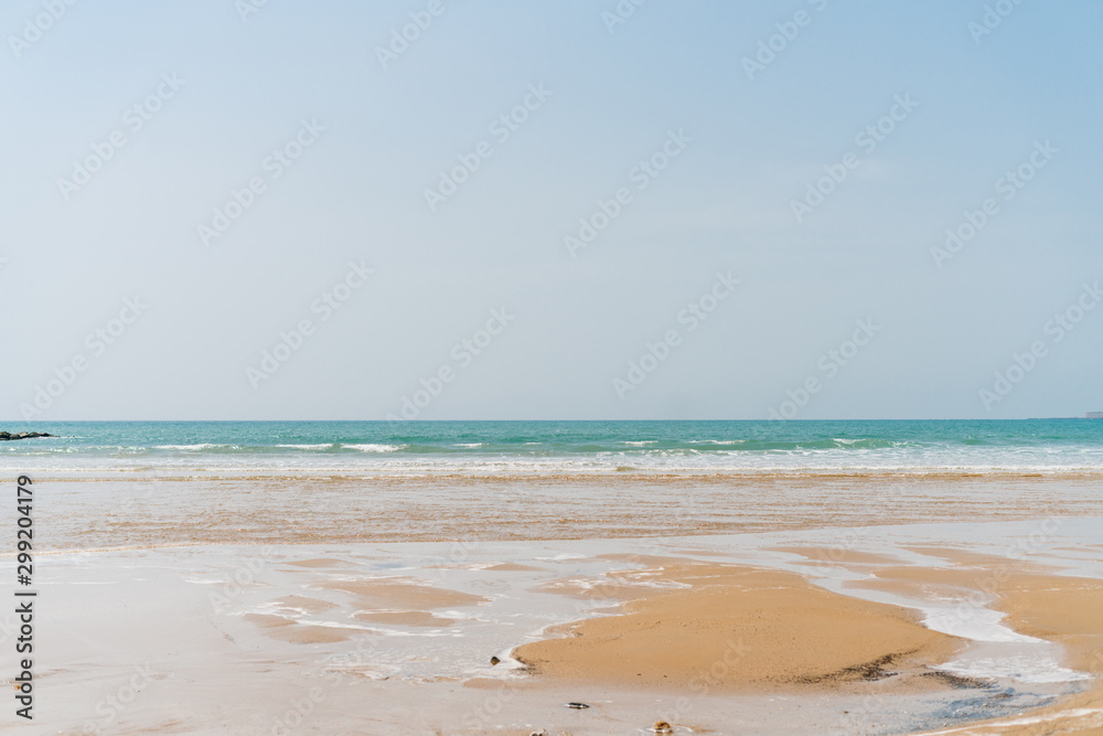 landscape of the ocean and sand over which the water spills