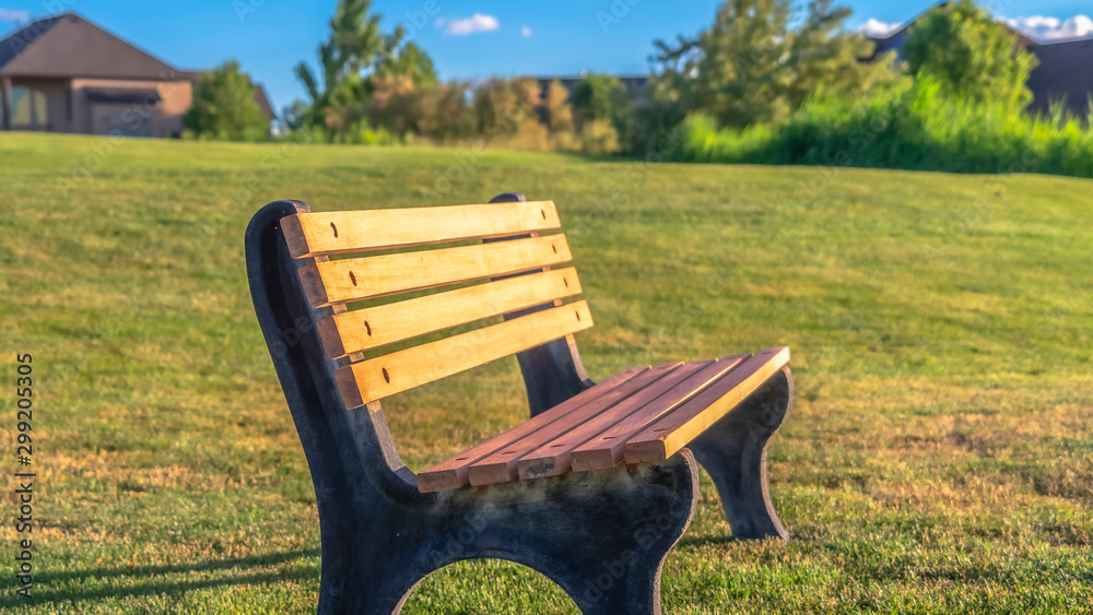 Panorama Focus on an empty outdor bench against short green grasses on a sunny day Panorama Focus on an empty outdor bench against short green grasses on a sunny day