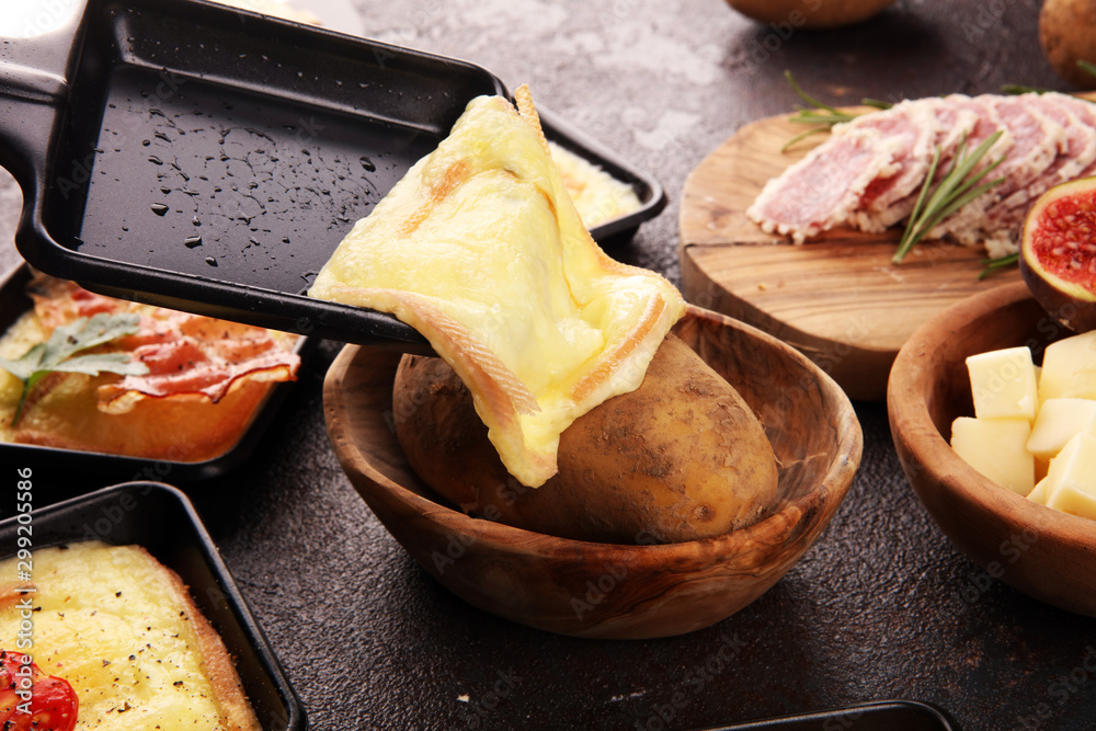 Delicious traditional Swiss melted raclette cheese on diced boiled or baked potato. - obrazy, fototapety, plakaty 
