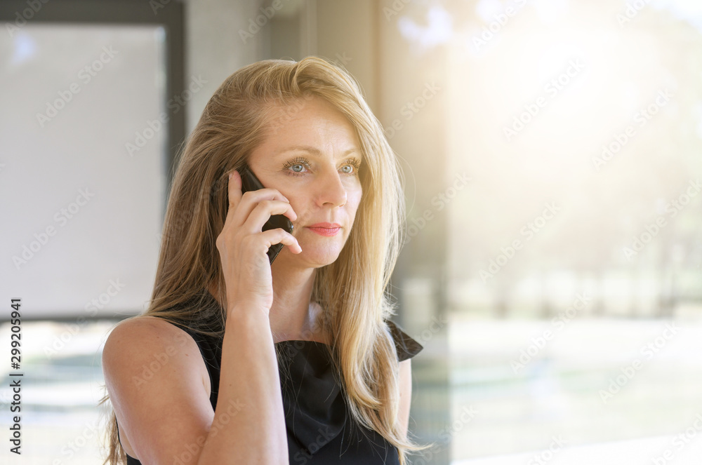 Middle aged business woman in office talking on cellphone Middle aged business woman in office talking on cellphone