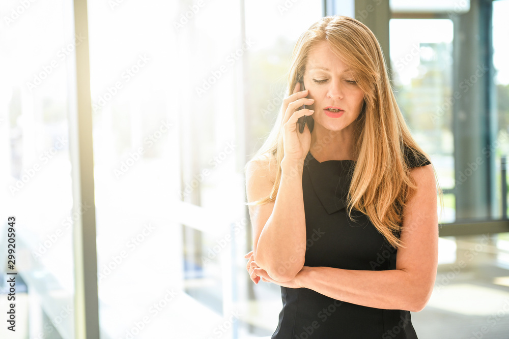 Middle aged business woman in office talking on cellphone Middle aged business woman in office talking on cellphone