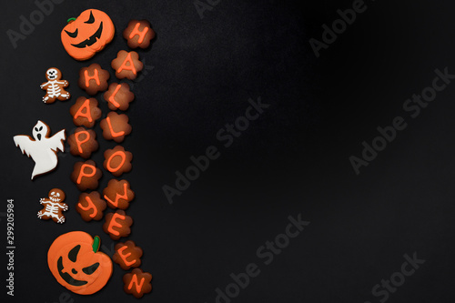 The hand-made eatable gingerbread Halloween inscription, pumpkin, ghosts, bat and sceletons on black background photo