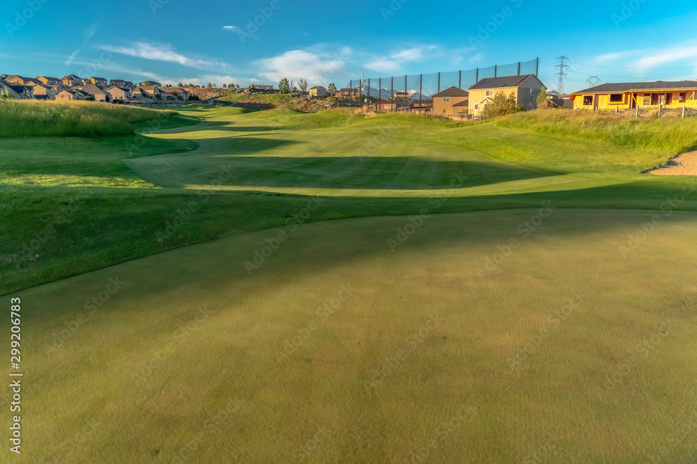 Scenic view of houses around a golf course under blue sky on a sunny day Scenic view of houses around a golf course under blue sky on a sunny day