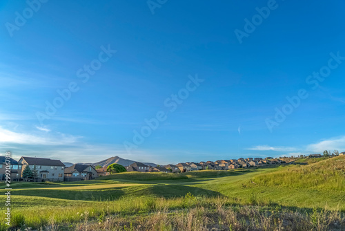 Grass covered golf course with homes in the background viewed on a sunny day