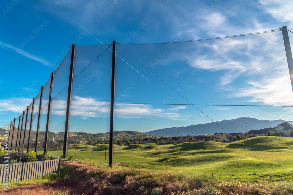 Fence with golf course homes and mountain against blue sky on the other side