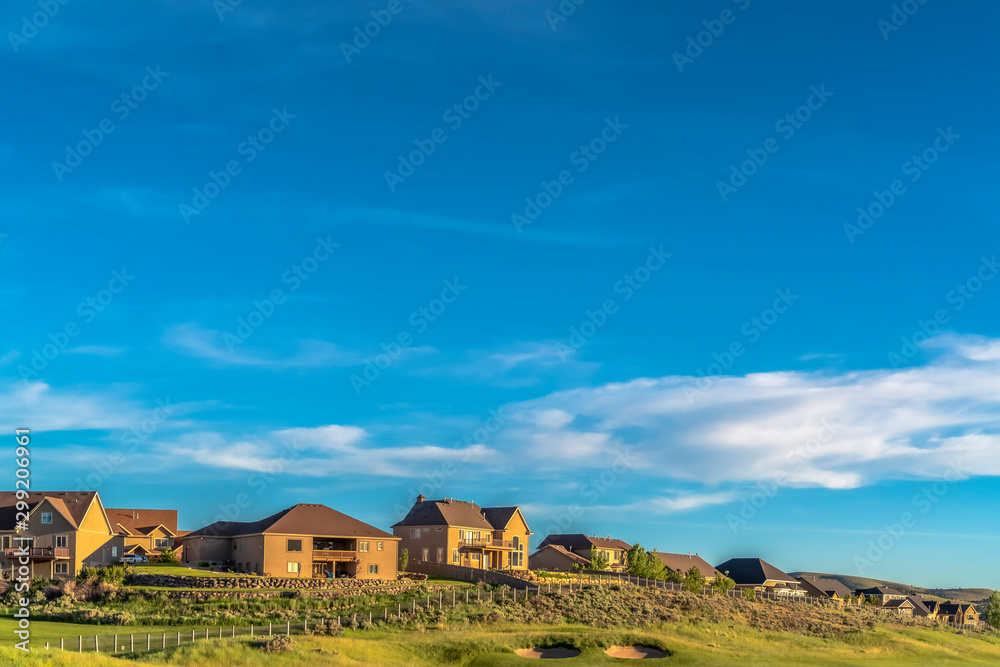 Sunny day view of multi storey houses with golf course in the foreground