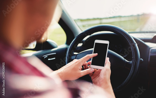 Man typing a message while driving a car, close up photo. Dangerous driving. Transportation concept