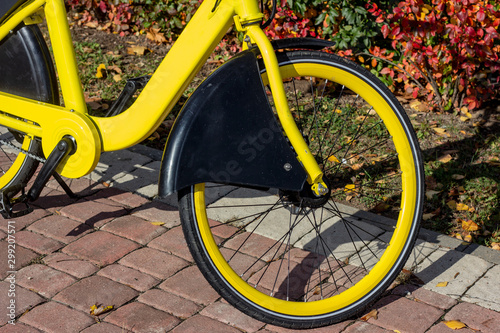 Bright yellow bicycle wheel standing  in the city street in autumn season. photo