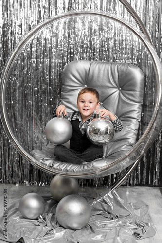Little boy plays in a chair a glass bowl with silver balls