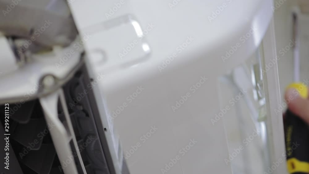 Professional maintenance of home air conditioners, the engineer unscrews and removes the top plastic cover Professional maintenance of home air conditioners, the engineer unscrews and removes the top plastic cover