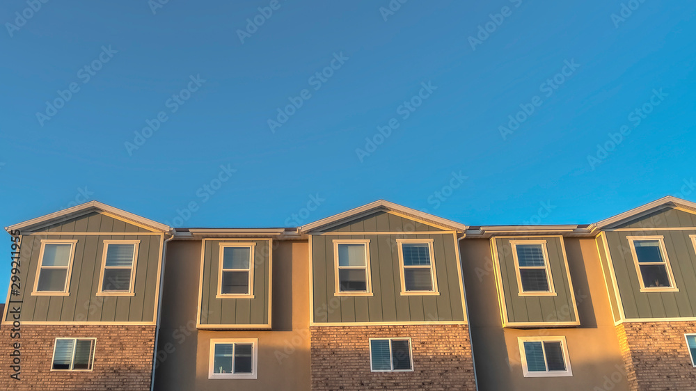 Panorama Upper storey of townhomes viewed from below against blue sky on a sunny day