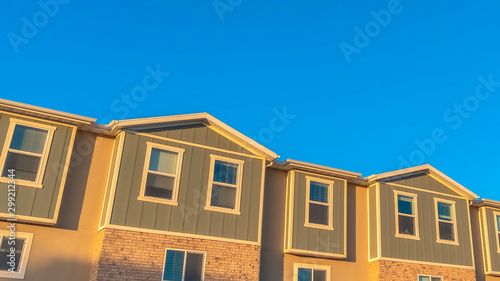 Panorama Facade of townhouses illuminated by sunlight with vibrant blue sky background