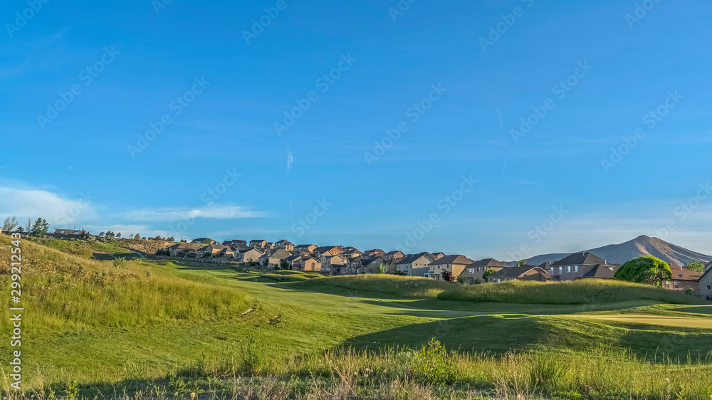 Panorama frame Grass covered golf course with homes in the background viewed on a sunny day