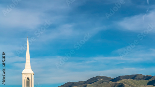 Photo Panorama Rooftop and steeple of a church against power lines mountain and blue s