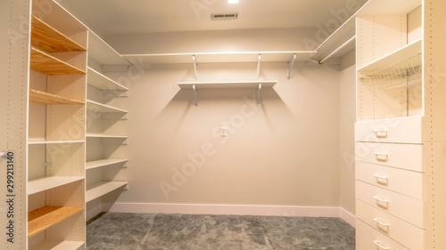 Panorama Empty walk in closet of a new house with shelves cabinets and clothes hangers