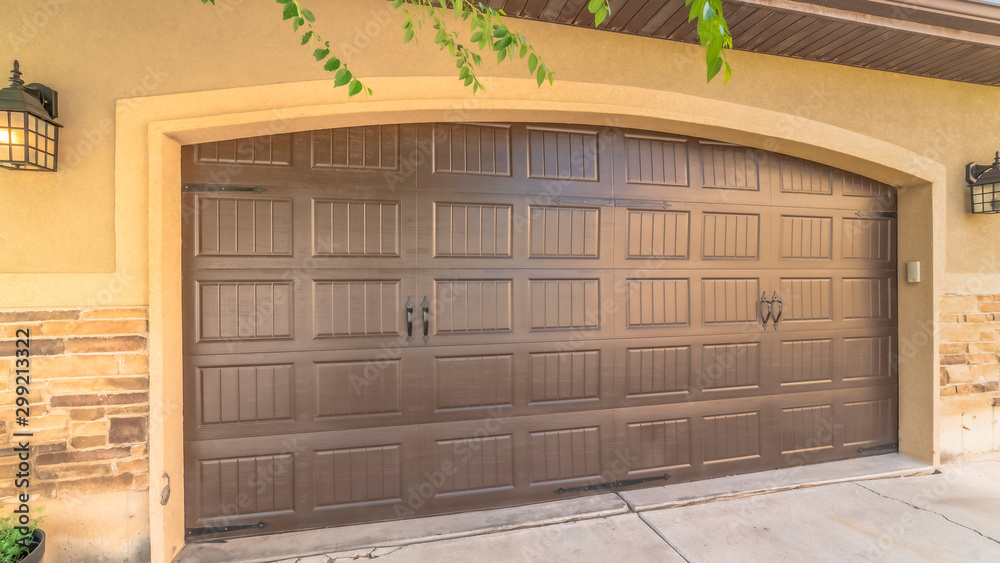 Panorama Garage door with an arched design against the concrete and brick wall of a home Panorama Garage door with an arched design against the concrete and brick wall of a home