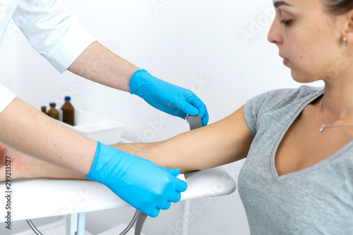 a gloved nurse removes a sterile needle from its packaging in front of the patient. Blood sampling procedure.