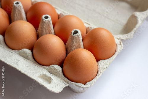 Stack of many brown and speckled fresh raw chicken eggs in the cardboard tray box packaging for sale in supermarket.